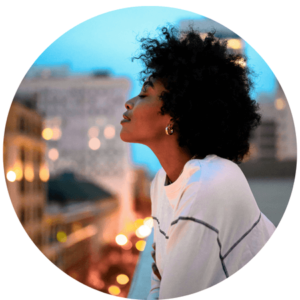 African American woman leaning over cityscape with her eyes closed wearing white sweater